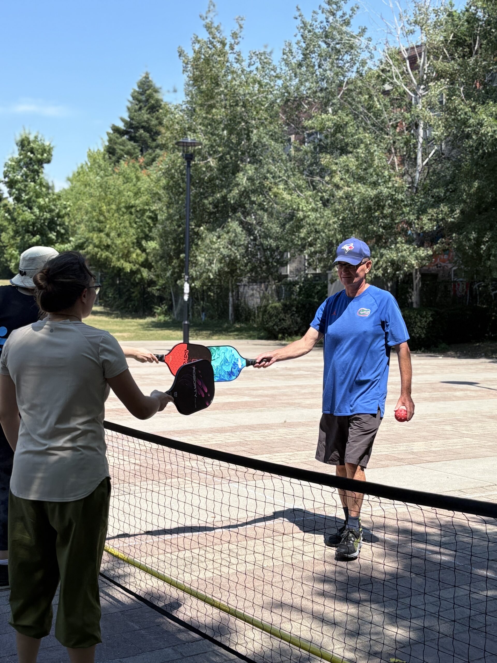 One player passing a pickleball paddle to another across the net