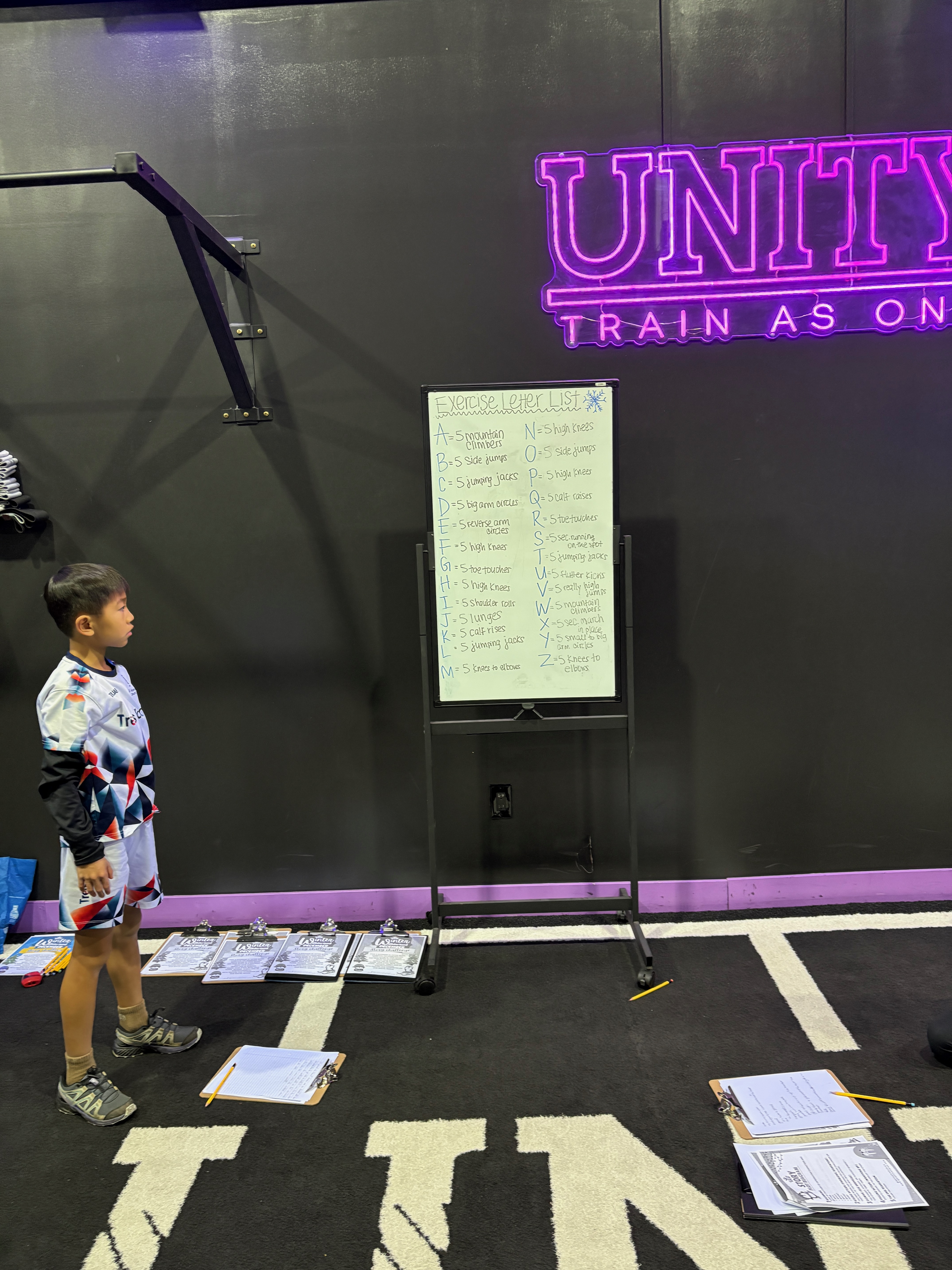 A boy reads the Exercise Letter List on a whiteboard, with a move for every letter from A to Z