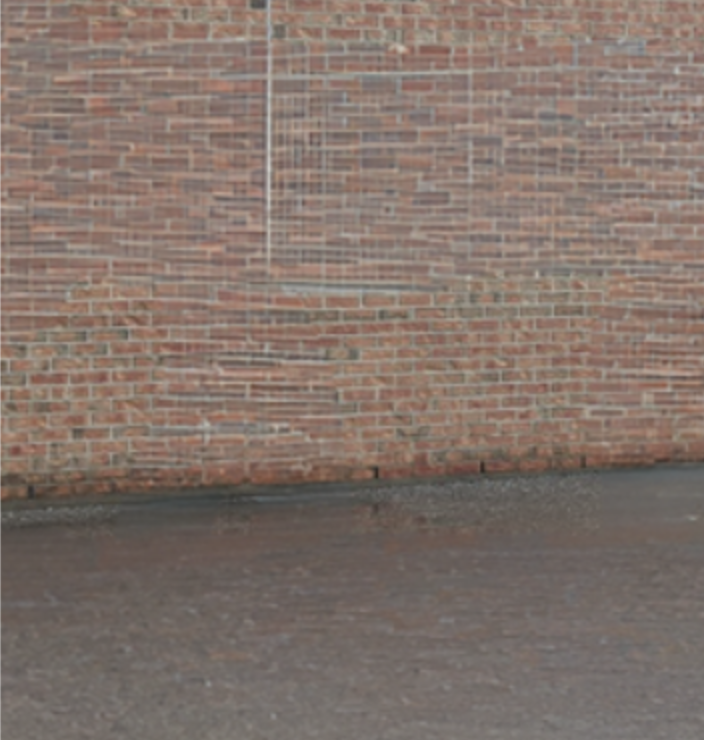 A bare schoolyard wall before a Sportswall was painted
