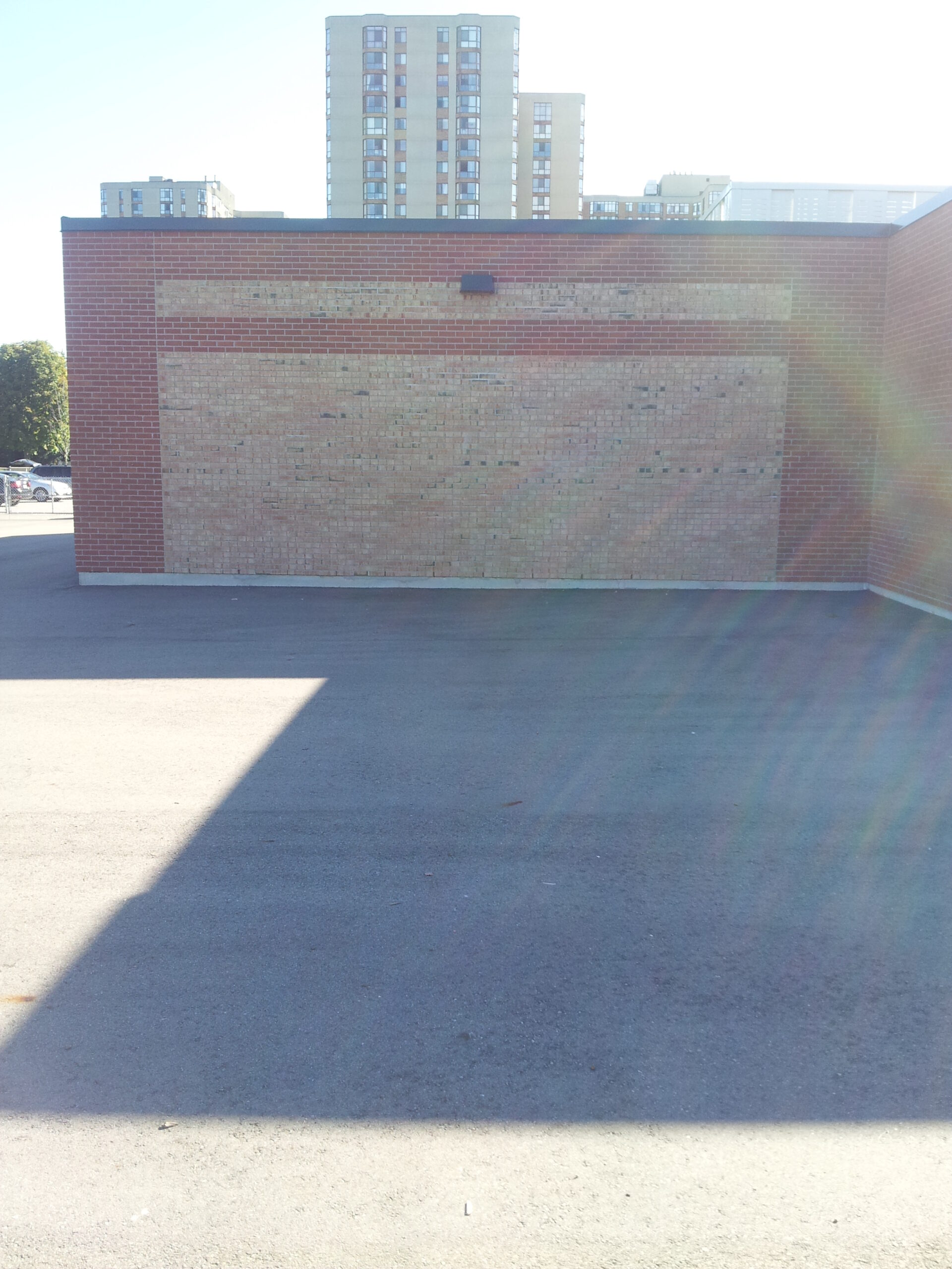 A bare schoolyard wall before a Sportswall was painted